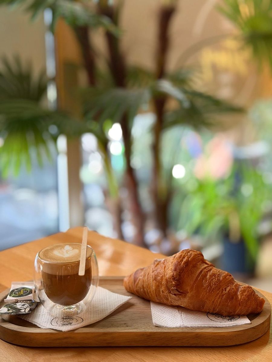Espresso i kroasan na drvenom poslužavniku u bašti kafića
