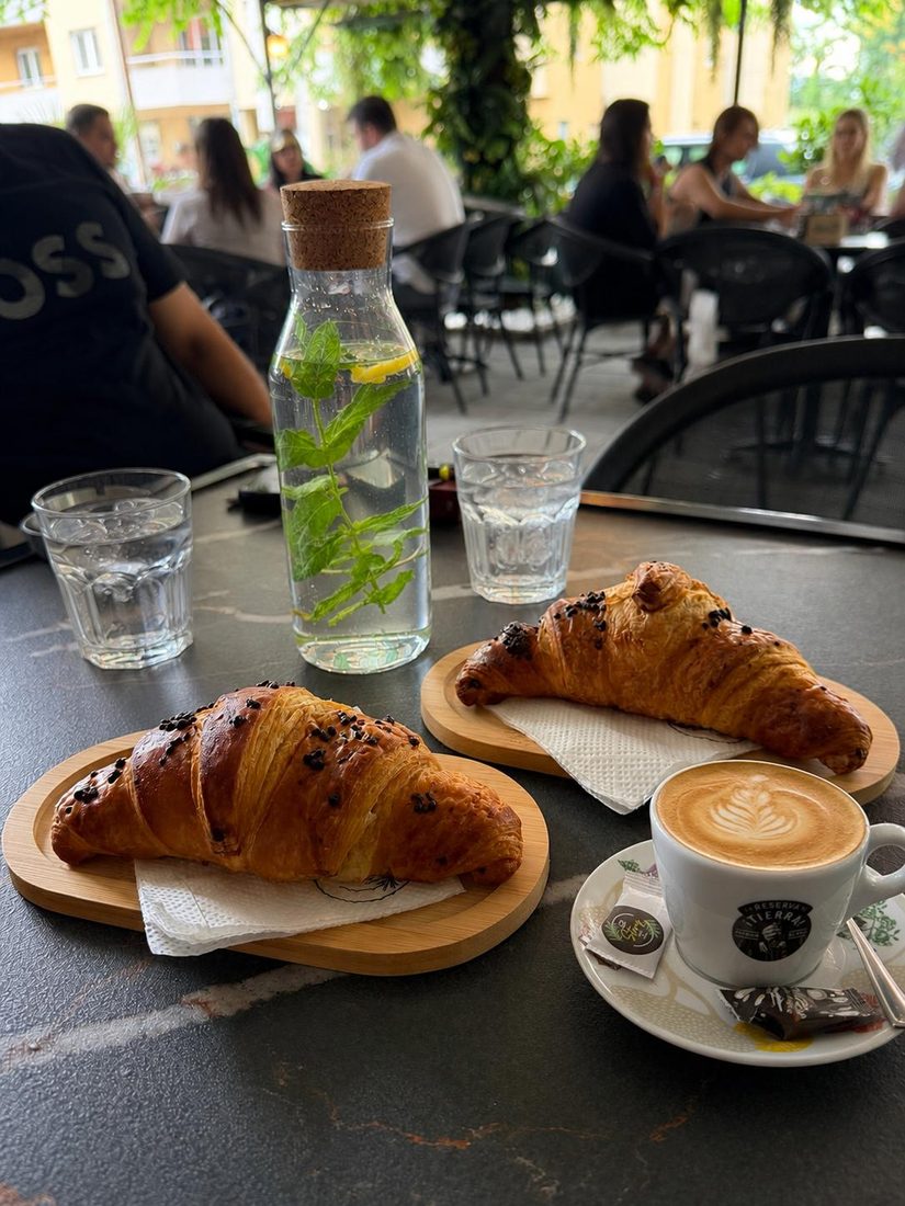 Dva kroasana sa čokoladom i cappuccino u bašti kafića