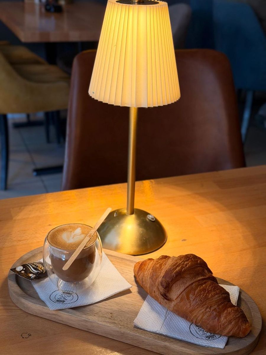 Topli napitak i kroasan pod svetlošću lampe